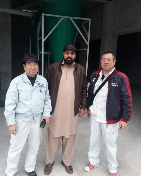 Three staff members, two of them Japanese technical partners, standing in a processing plant.