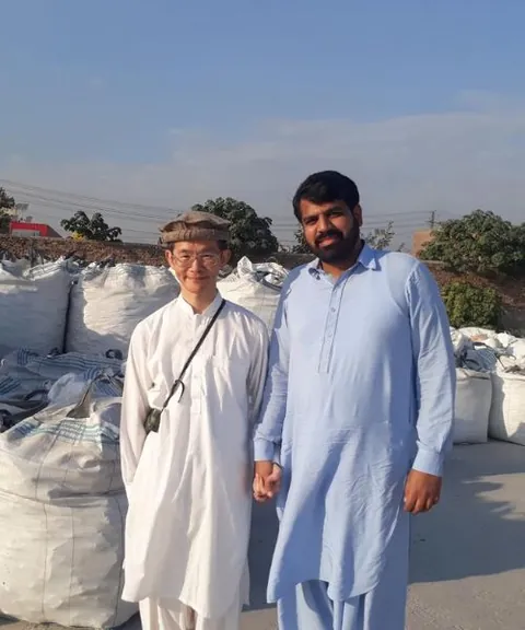 Two men standing in a yard of filled jumbo bags.