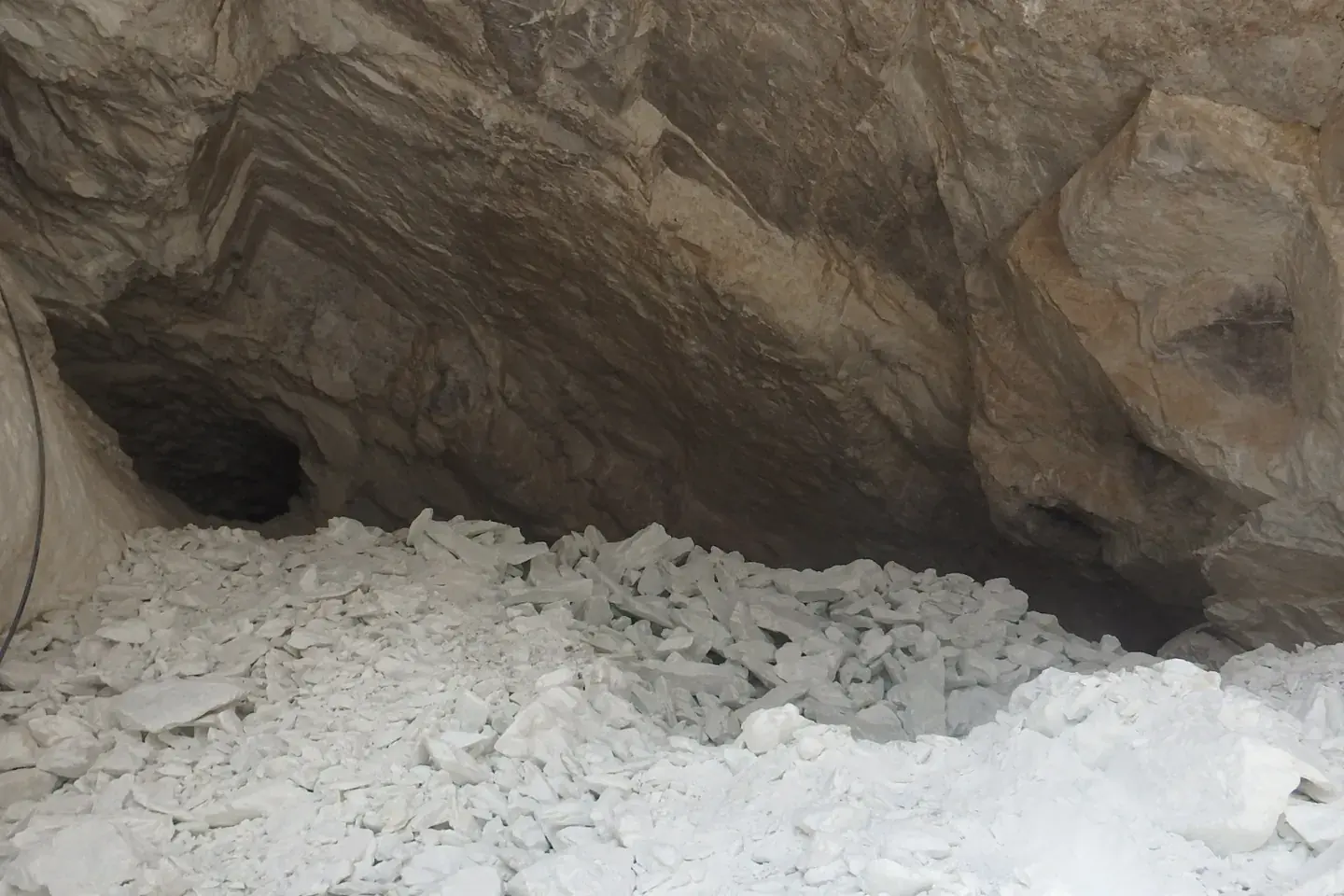 Broken white rock inside a dimly lit underground chamber.