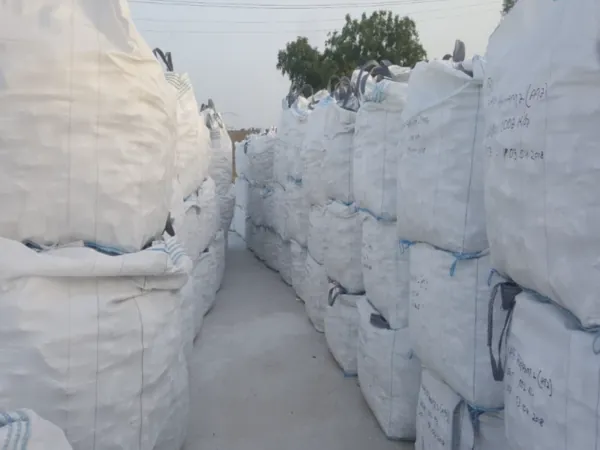 Corridor between tall rows of stacked white jumbo bags.