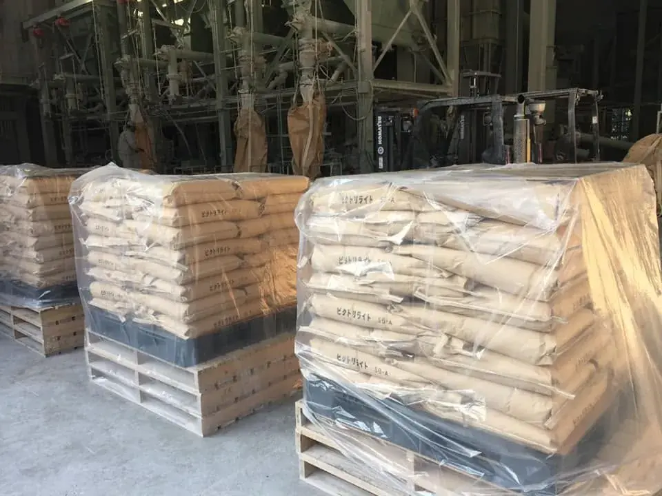 Shrink-wrapped pallets of stacked paper bags in a warehouse.