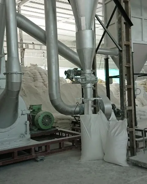 Silver grinding mill with piping and filled bags beside a powder stockpile.