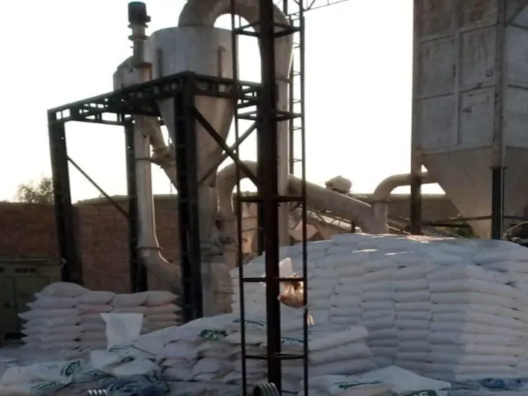Raymond-type grinding mill beside stacked SKZ talc powder bags.