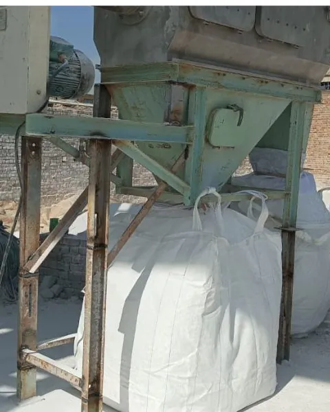 White powder being filled into a jumbo bag under a hopper and dust collector.