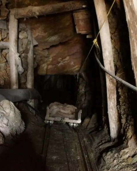 Timber-supported underground adit with rail track and a mine cart.