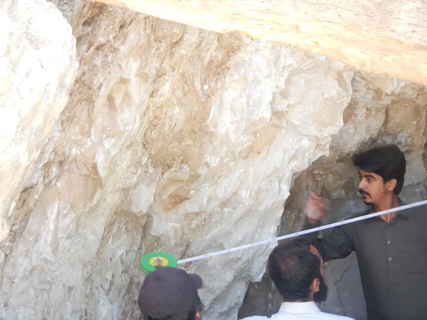 Surveyors measuring with a tape inside a cream-coloured rock adit.