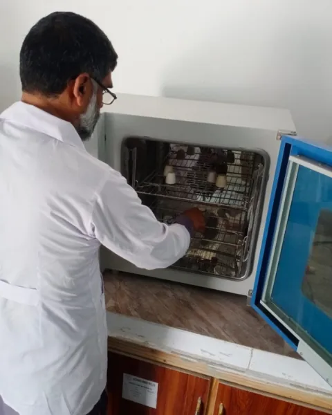Laboratory technician placing samples into a drying oven.