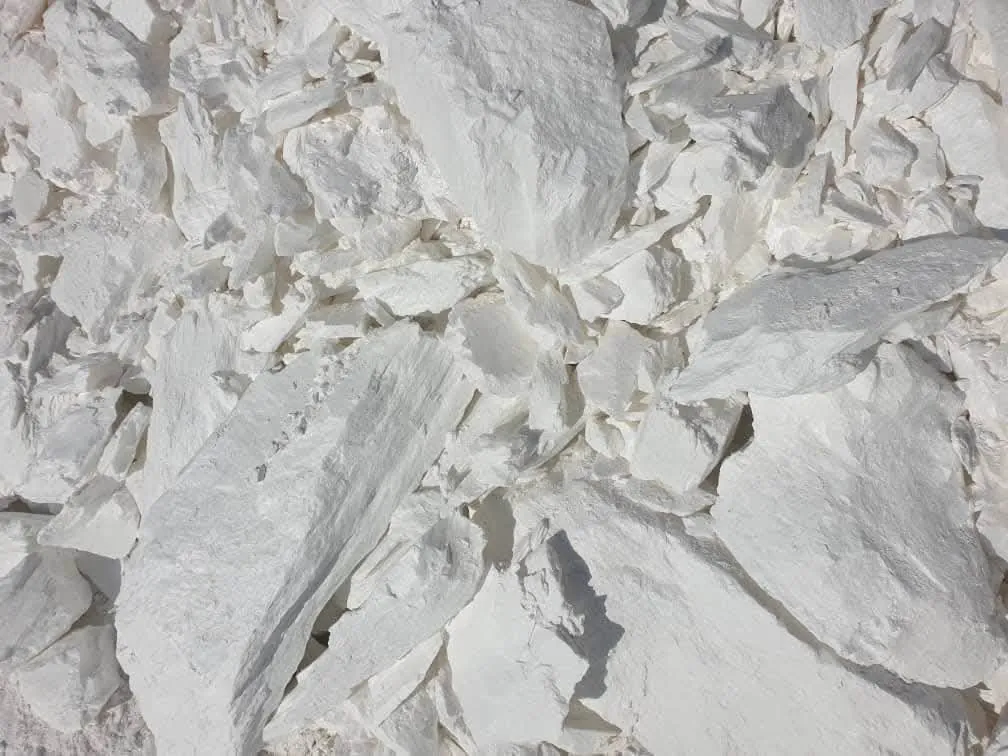 Close-up of white foliated talc lumps showing flat, layered plates.